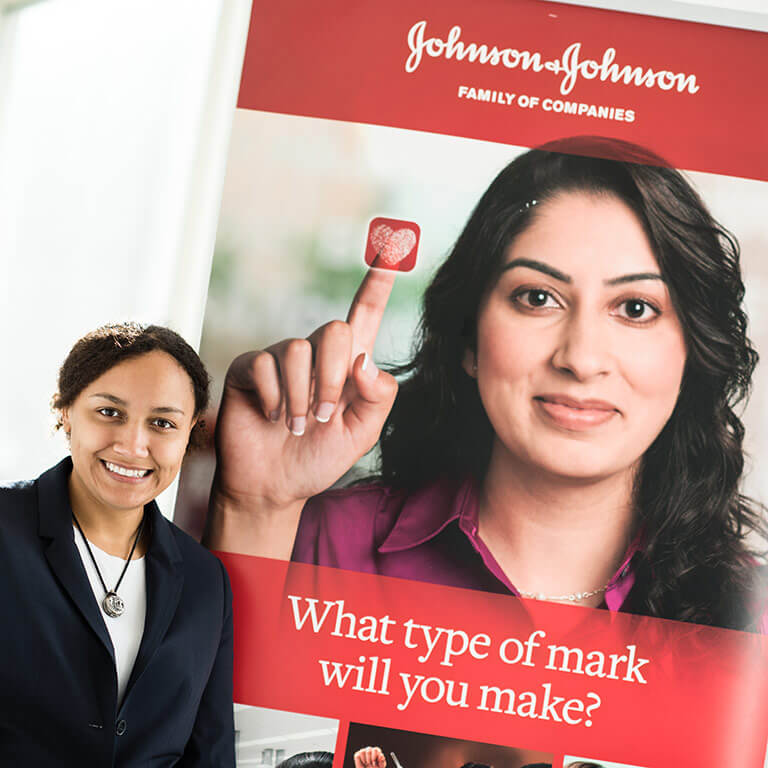A Kelley School of Business student stands in front of a Johnson and Johnson sign at a Center for the Business of Life Sciences event. 